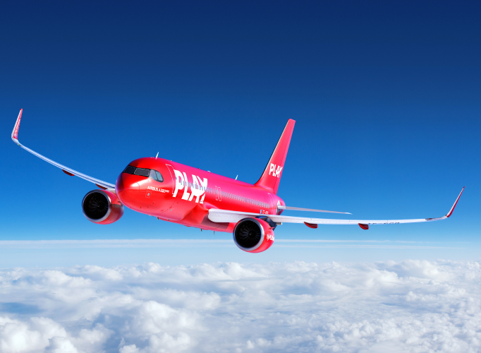 PLAY aircraft flying above clouds with blue sky in the background.